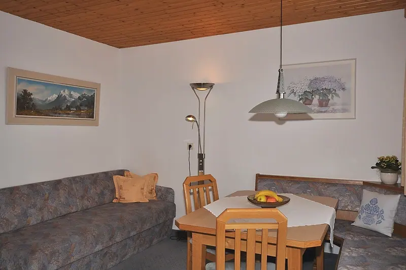 Wohnraum mit Eckbank, Esstisch und Couch unter der Holzdecke
